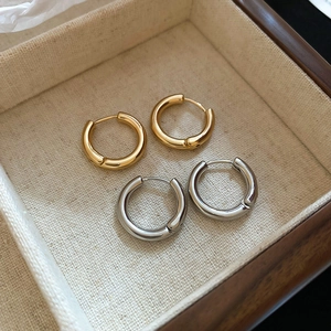 Close-up of gold and silver polished round hoop earrings in a cream jewelry box