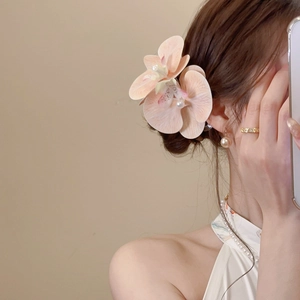 Detail of pink fabric flower hair clip with white pearl on model showing elegant side view