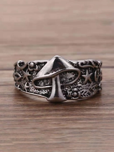 Macro shot of vintage silver mushroom ring with star and leaf relief on wood surface