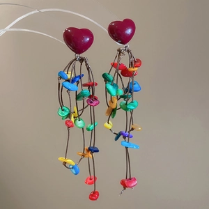 Close-up of heart studs with dangling colorful shell beads on bohemian tassel earrings