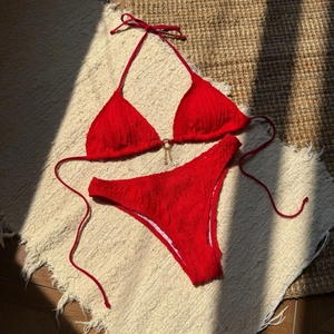 Detail of red bikini featuring wavy textured fabric and gold seashell star charms