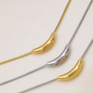 Detailed view of polished metallic curved tube pendants on gold and silver snake chains
