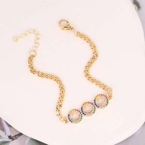 Macro detail of gold Cuban chain bracelet with three colorful zircon inlaid smiley faces