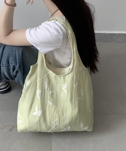 Close-up of light green lace tote bag featuring white branch and leaf embroidery details