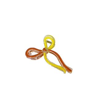 Bow-shaped hair claw clip with colorful yellow and orange ribbon patterns in acrylic