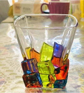 Detail view of colorful glass block base on a textured whisky glass with square rim
