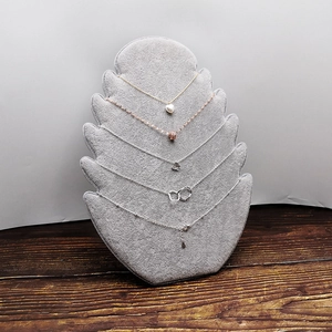 Set of gold and silver necklaces displayed on a gray velvet stand against wood background
