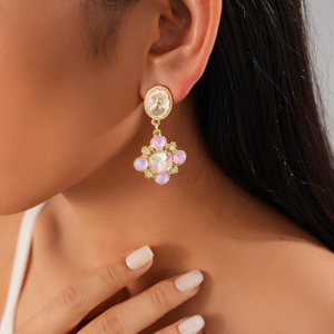 Close-up of vintage flower drop earrings with colorful crystals worn by a model