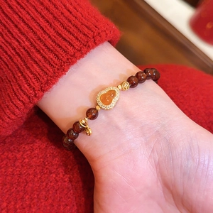 Detailaufnahme eines roten Achat-Armbands mit goldenem Kürbis und Münzanhänger