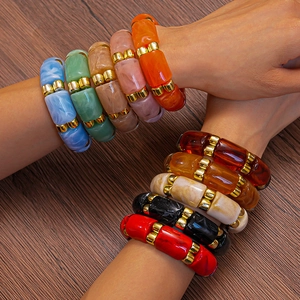Close-up of colorful geometric acrylic resin bracelets with gold spacer beads on wrist