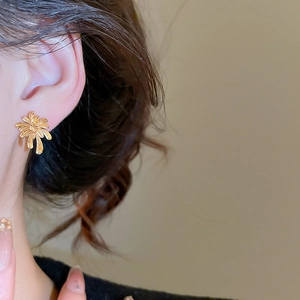 Close-up of gold-plated firework earrings worn by model for a French vintage aesthetic look