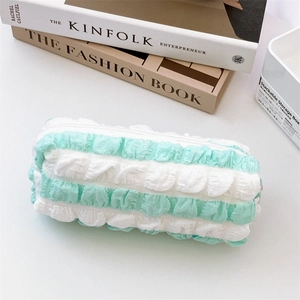 Detailed view of mint green striped pencil case with ruffled edges and smooth zipper