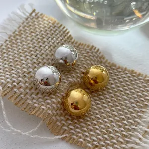 Detailed macro view of 925 sterling silver ball earrings in gold and silver mirror finish