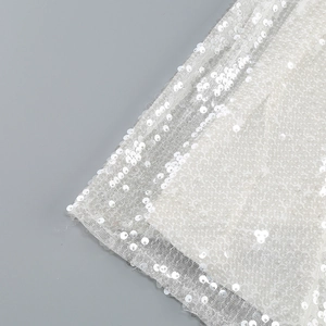 Close-up of sparkling silver sequins and mesh fabric on an elegant floor-length dress