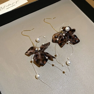 Detailed close-up of brown leopard acrylic flower earrings with white pearls and gold hooks