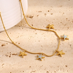 Detail of 18K gold plated snake chain necklace with colorful starfish pendants