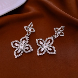 Macro shot of silver flower earrings with crystals on luxury brown satin fabric