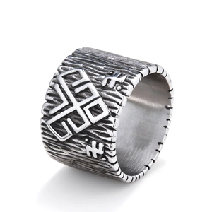 Vintage stainless steel wide ring with tribal symbols and wood grain texture on white background