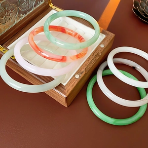 Detail of round resin agate bangles in various colors displayed in a retro wooden gift box