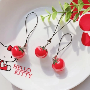 Three realistic tomato phone charms with green stalks on a ceramic plate for gifts