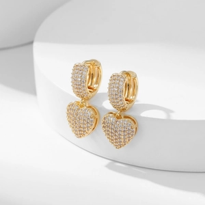 Micro-pave zircon heart drop earrings in gold finish on minimalist white steps display