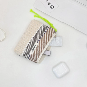 Detail of handwoven striped makeup pouch with vibrant green pull and Sozakka label