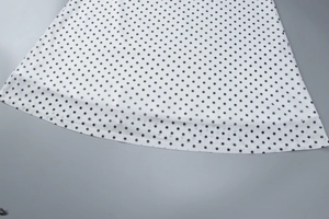 Detailed view of white fabric with black polka dots featuring subtle mesh texture