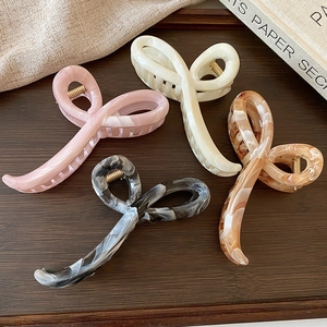 Close-up of marble acetate hair claws in pastel colors on a vintage wooden tray