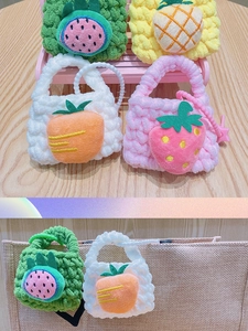 Mini hand-knitted fruit charms including strawberry and pineapple on a canvas bag