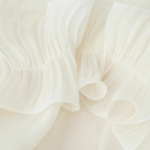 Close-up of white ruffled chiffon fabric with elegant vertical pleats and hem details