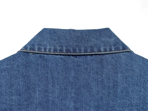 Gros plan du col d'une chemise en jean bleu foncé avec des coutures brunes détaillées