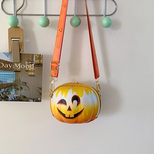 Detail of pumpkin-shaped crossbody bag featuring a smiling face and orange gradient finish