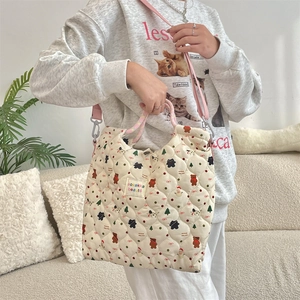 Close-up of quilted canvas crossbody bag featuring cartoon bear prints and pink handles