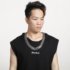 Close-up of a wide chunky silver Cuban chain necklace worn by a male model on a plain background