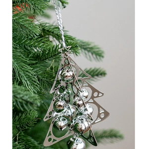 Silver metal hollow Christmas tree ornament with bell charms hanging on a pine branch