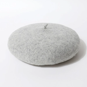 Detailopname van een minimalistische grijze wollen vilt baret met een klassiek steeltje.