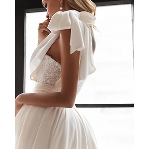 Detail of white sequined bodice and oversized satin shoulder bow on formal dress