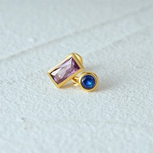 Macro view of gold S925 silver stud earring with purple rectangle and blue round gems