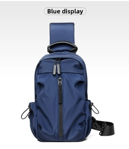 Front detail of blue nylon crossbody bag featuring vertical zipper and top handle