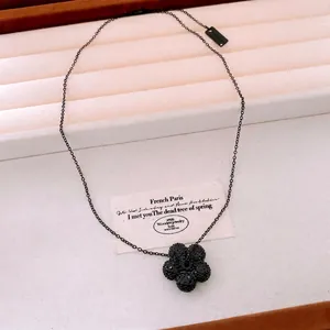 Minimalist black flower pendant necklace with shimmering crystals on white display