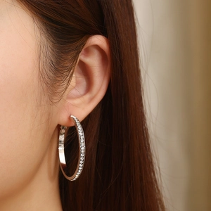 Détail de grandes créoles argentées avec strass brillants portées par un mannequin femme