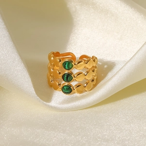 Vue détaillée d'une bague dorée à trois rangs sertie de malachite sur soie beige