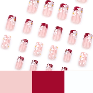 Short square press-on nails with red French tips and white daisy floral patterns