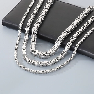 Polished silver stainless steel Byzantine chain necklace on black leather surface