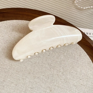 Gros plan d'une pince à cheveux en acrylique marbré blanc crème sur fond de luxe