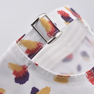 Close-up of the metal buckle and colorful print detail on a white cotton baseball cap