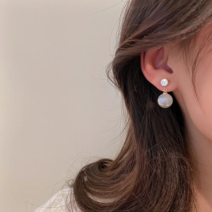 Détail de boucles d'oreilles perles dorées élégantes avec zircon sur l'oreille
