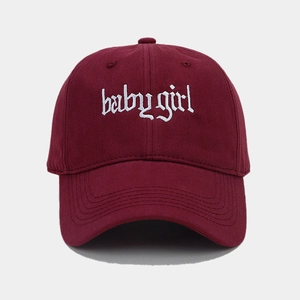 Close-up of white baby girl embroidery on a burgundy cotton baseball cap with curved brim