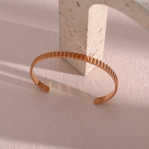 Macro view of rose gold open cuff bracelet with elegant vertical stripe texture design