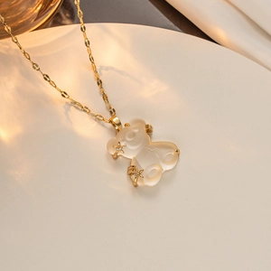 Detail shot of golden teddy bear pendant with star accents on minimalist white tray
